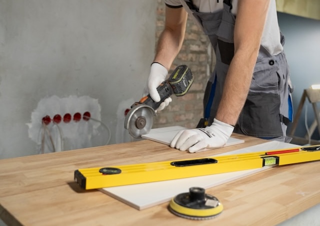 A man sanding a wooden table with a sander